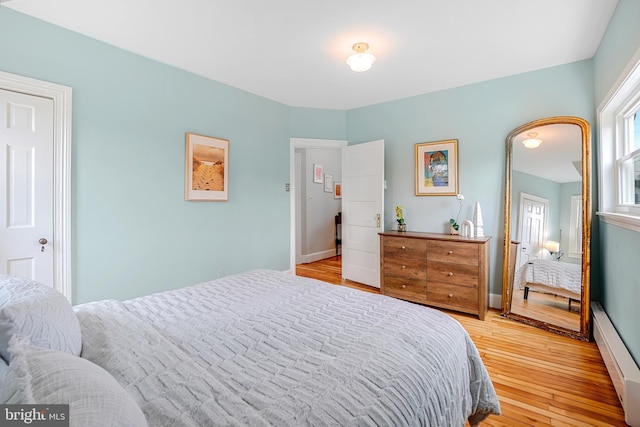 bedroom featuring a baseboard heating unit and light wood-type flooring