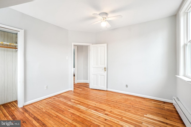 unfurnished bedroom with a closet, ceiling fan, baseboard heating, and light hardwood / wood-style floors