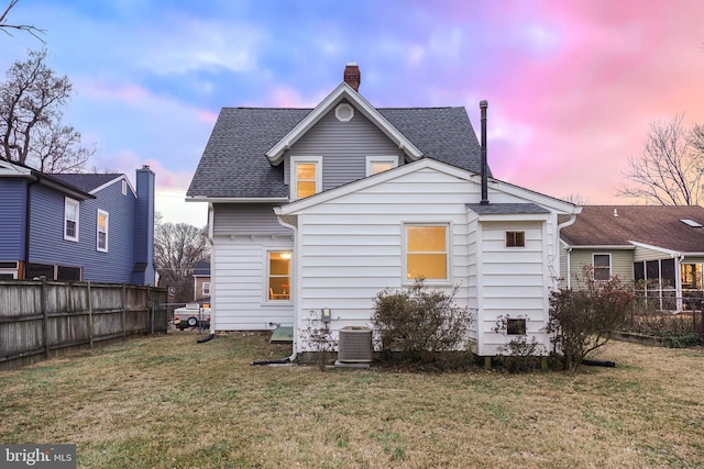 back house at dusk with cooling unit and a yard