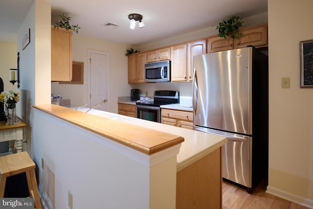 kitchen featuring sink, kitchen peninsula, stainless steel appliances, light brown cabinets, and light wood-type flooring