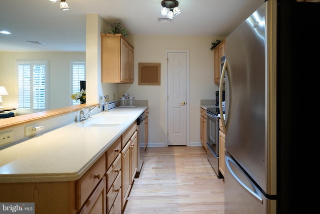 kitchen with sink, light brown cabinets, light hardwood / wood-style floors, and appliances with stainless steel finishes