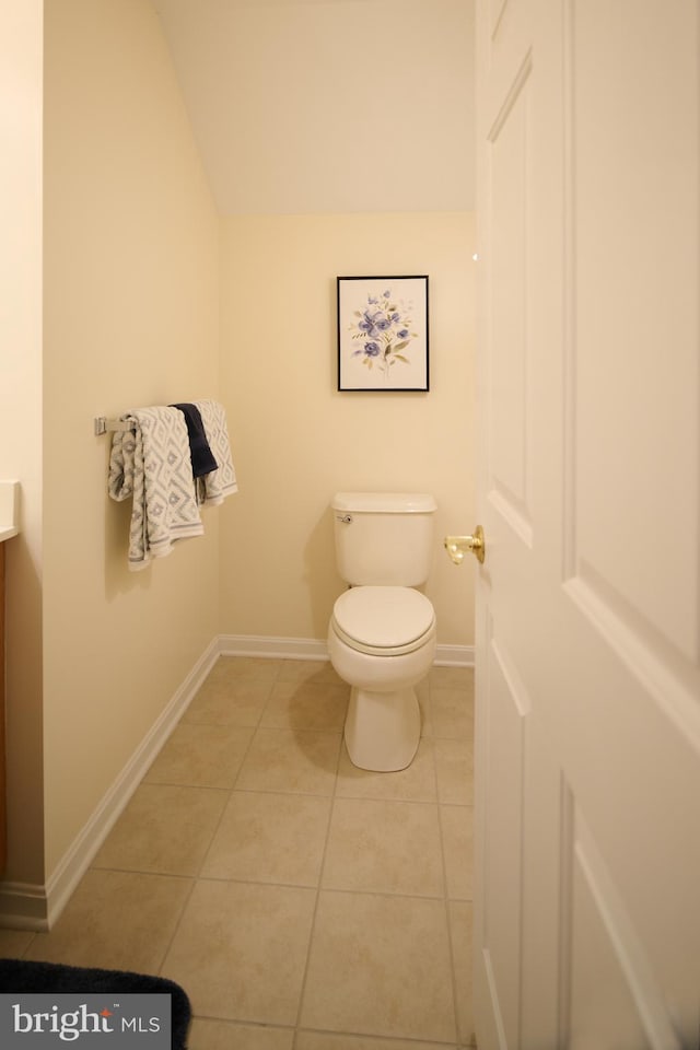 bathroom featuring tile patterned flooring, vanity, lofted ceiling, and toilet