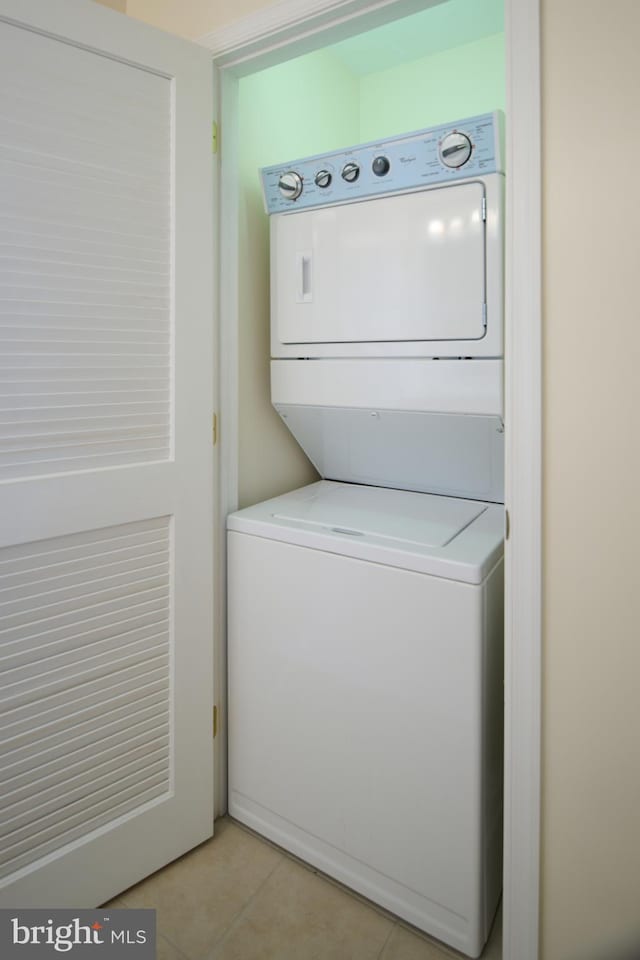 clothes washing area with light tile patterned floors and stacked washer and clothes dryer