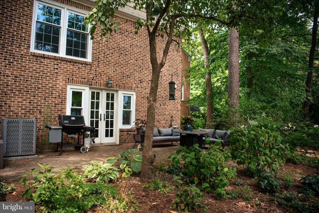 back of property with french doors, an outdoor living space, a patio area, and central air condition unit