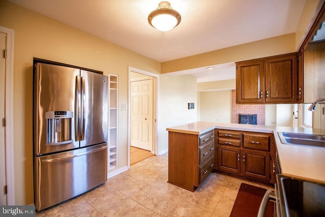 kitchen with sink, kitchen peninsula, stainless steel fridge with ice dispenser, and light tile patterned floors