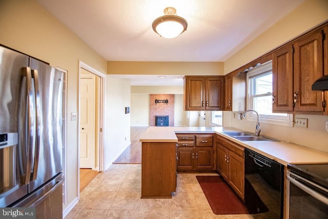 kitchen featuring light tile patterned flooring, sink, a brick fireplace, appliances with stainless steel finishes, and kitchen peninsula