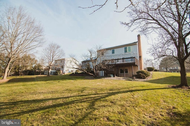 back of property with a wooden deck and a yard