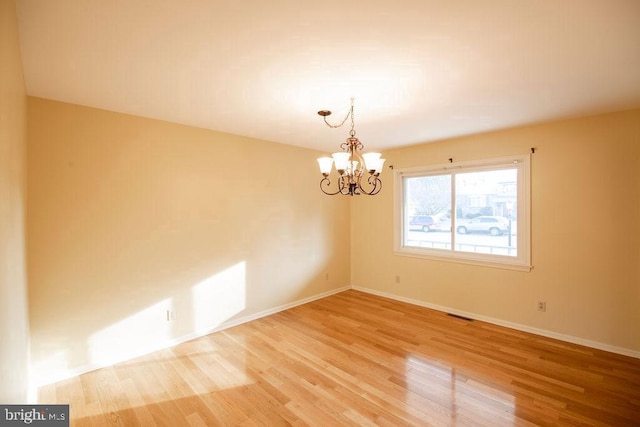 unfurnished room featuring wood-type flooring and an inviting chandelier