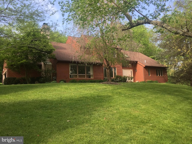 view of front of home with a garage, roof with shingles, a front lawn, and a chimney