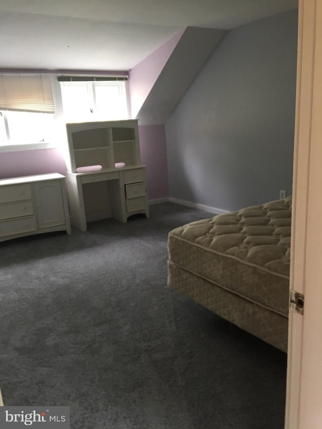 unfurnished bedroom featuring lofted ceiling and dark colored carpet