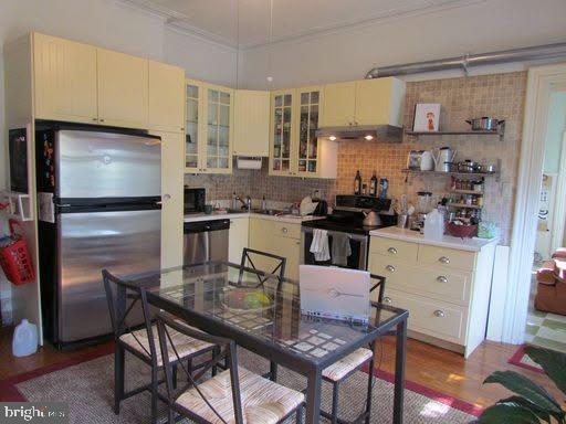 kitchen featuring tasteful backsplash, ornamental molding, stainless steel appliances, and wood-type flooring