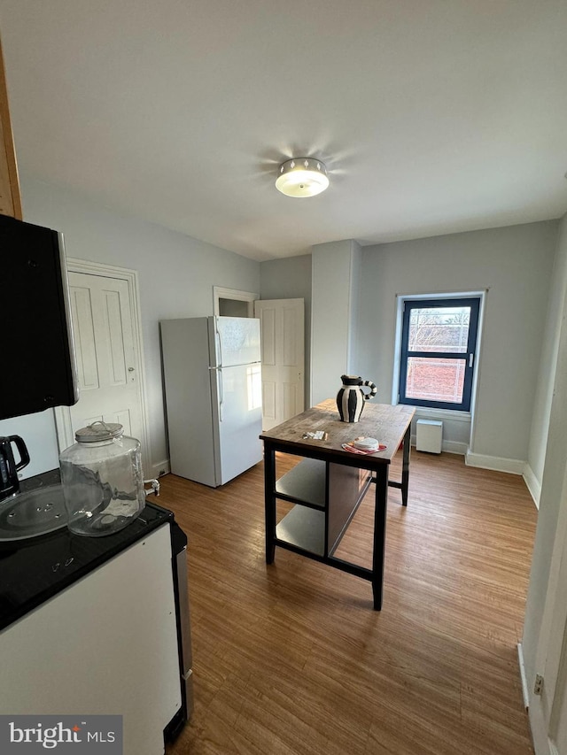 kitchen featuring white cabinetry, light wood-type flooring, stove, and white fridge