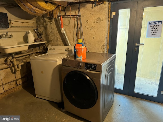 laundry area with french doors, washer and clothes dryer, and sink