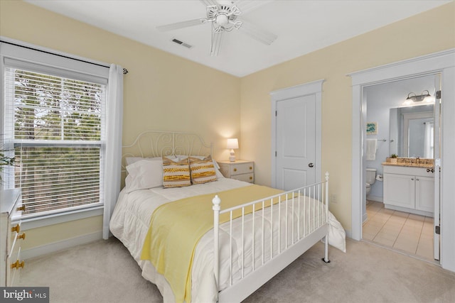 carpeted bedroom with a ceiling fan, baseboards, visible vents, a sink, and ensuite bathroom