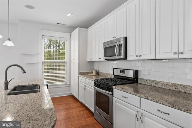 kitchen with decorative backsplash, white cabinets, appliances with stainless steel finishes, and a sink