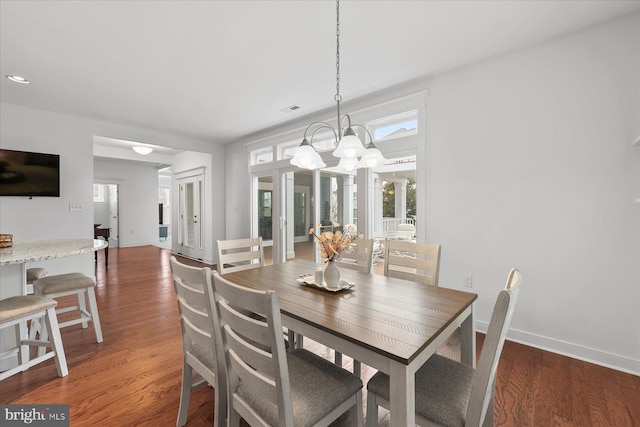 dining room with a notable chandelier, baseboards, visible vents, and wood finished floors