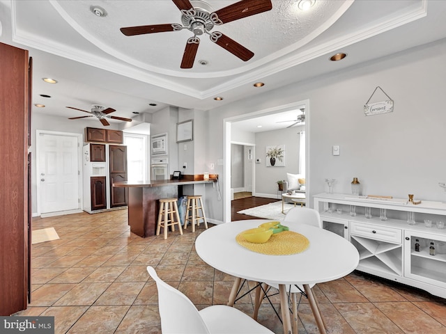 tiled dining space with a raised ceiling