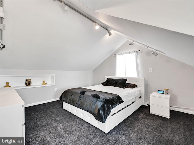 carpeted bedroom with lofted ceiling and rail lighting