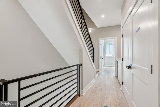 corridor with light wood finished floors, baseboards, and recessed lighting
