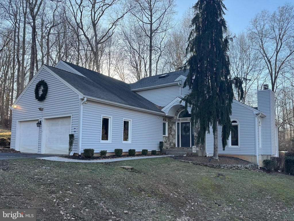 view of front of property with aphalt driveway, a chimney, and an attached garage