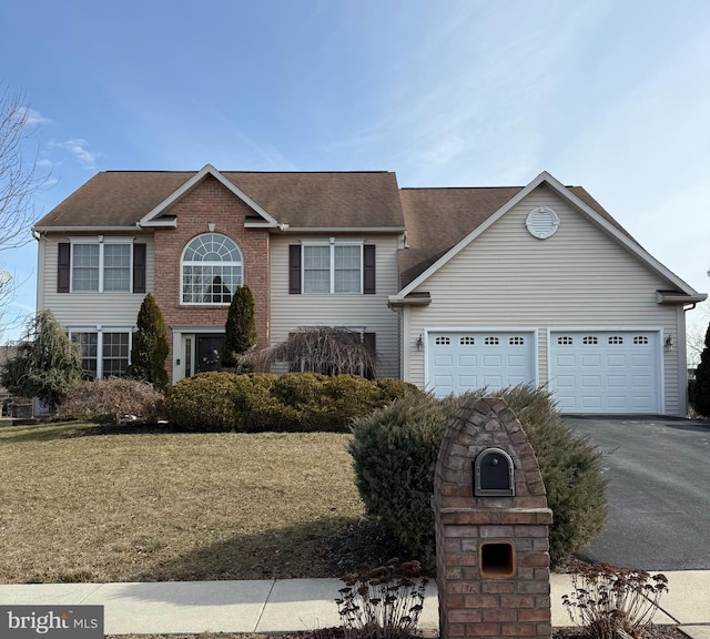 view of front of property featuring aphalt driveway, a garage, brick siding, a shingled roof, and a front yard