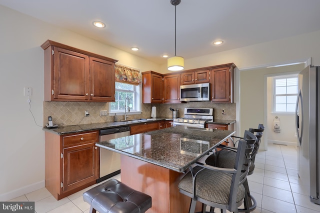 kitchen featuring stainless steel appliances, a sink, a kitchen bar, and tasteful backsplash