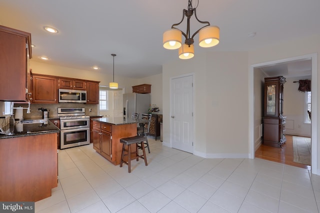 kitchen with decorative backsplash, a kitchen island, appliances with stainless steel finishes, pendant lighting, and a sink