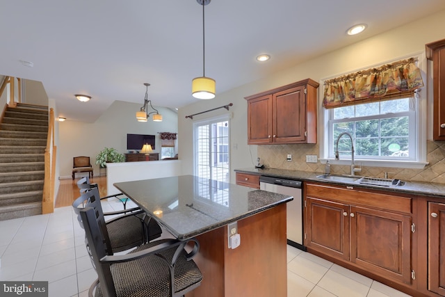 kitchen featuring a center island, a breakfast bar area, backsplash, a sink, and dishwasher