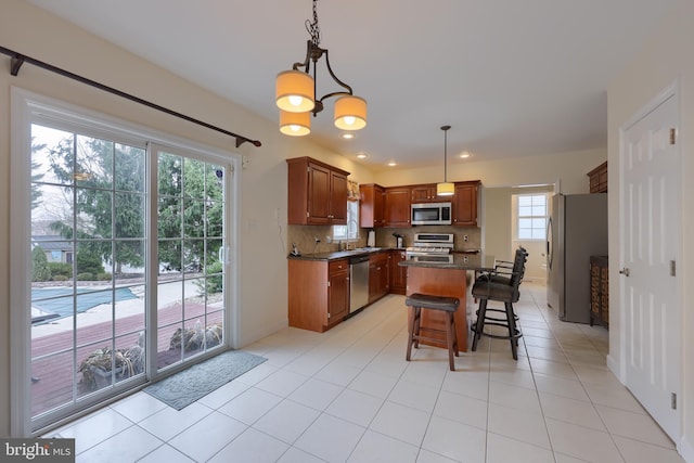 kitchen with tasteful backsplash, dark countertops, a center island, stainless steel appliances, and a sink