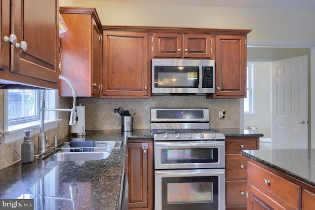 kitchen featuring stainless steel appliances, a wealth of natural light, a sink, and decorative backsplash