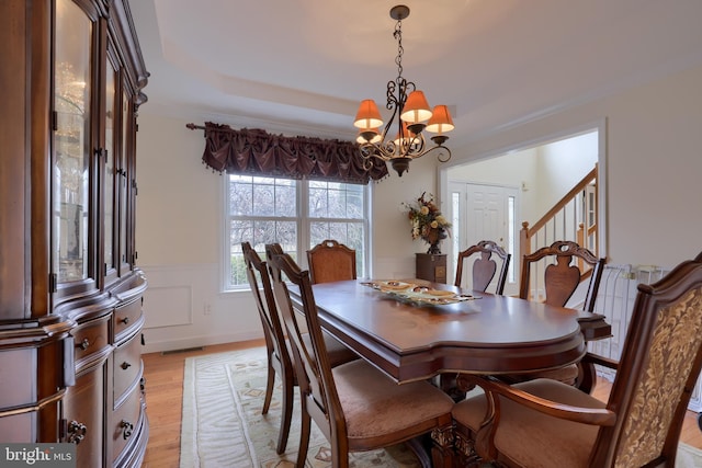 dining room featuring a chandelier, a wainscoted wall, visible vents, light wood-style floors, and crown molding