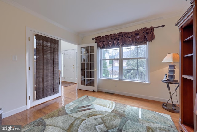 interior space featuring visible vents, baseboards, crown molding, and wood finished floors