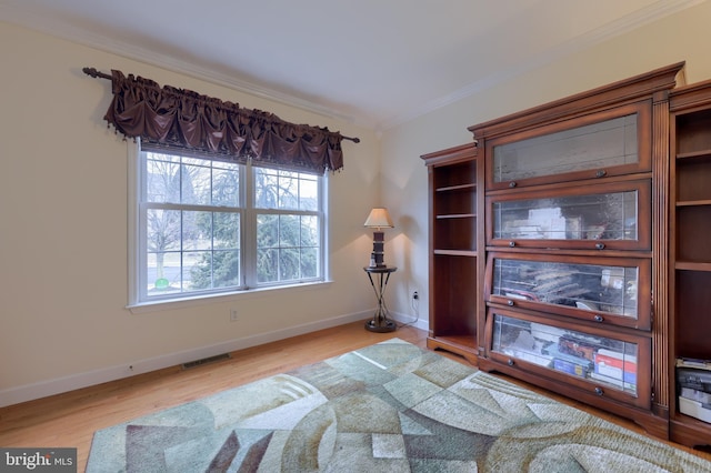 living area with ornamental molding, visible vents, baseboards, and wood finished floors