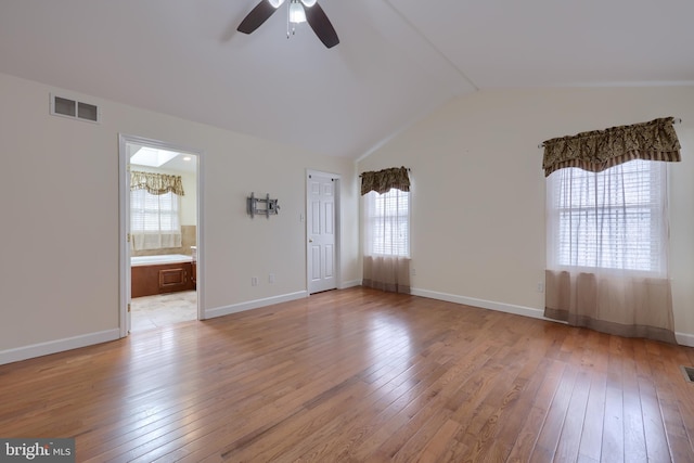 unfurnished room featuring lofted ceiling, light wood-style floors, baseboards, and visible vents