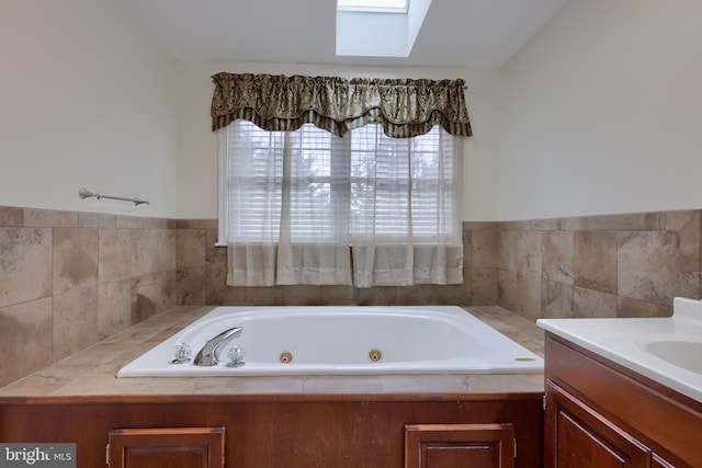 full bath with a tub with jets, a skylight, and vanity