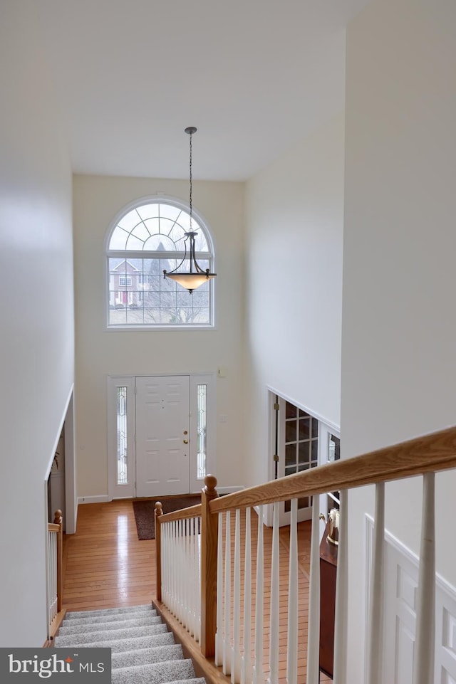 entrance foyer with stairs, light wood-type flooring, and a towering ceiling