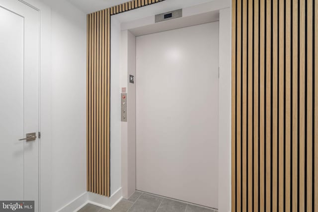 hall featuring light tile patterned floors and elevator