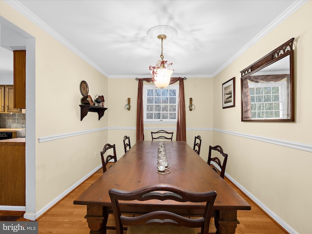 dining area with plenty of natural light, crown molding, and light wood-style flooring