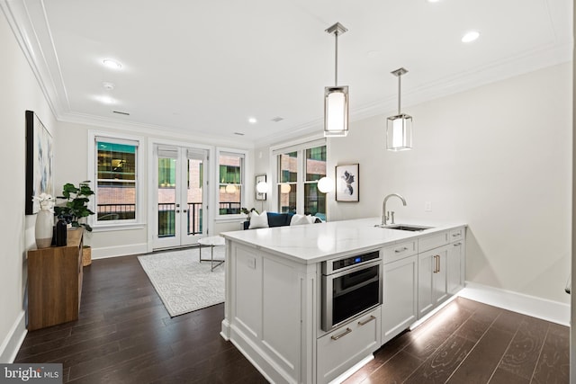 kitchen with pendant lighting, french doors, white cabinetry, a sink, and oven