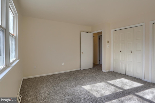 unfurnished bedroom featuring multiple windows, baseboard heating, and carpet flooring