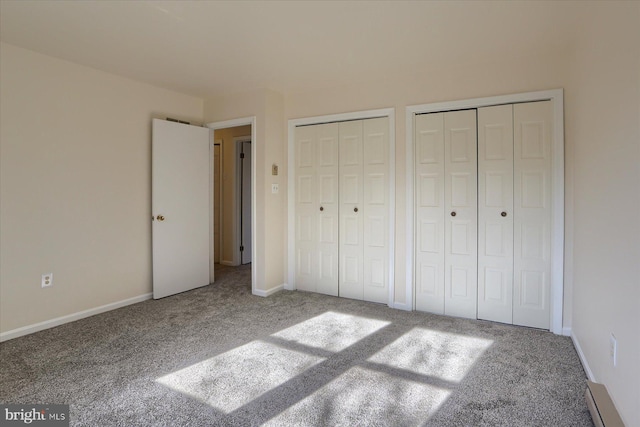 unfurnished bedroom with carpet flooring and two closets