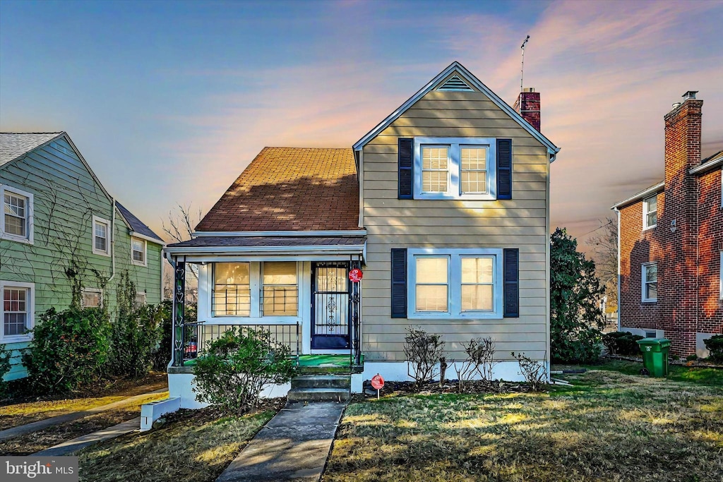 traditional-style house featuring covered porch and a lawn