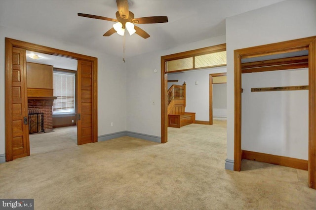 unfurnished bedroom featuring a brick fireplace, light colored carpet, and ceiling fan