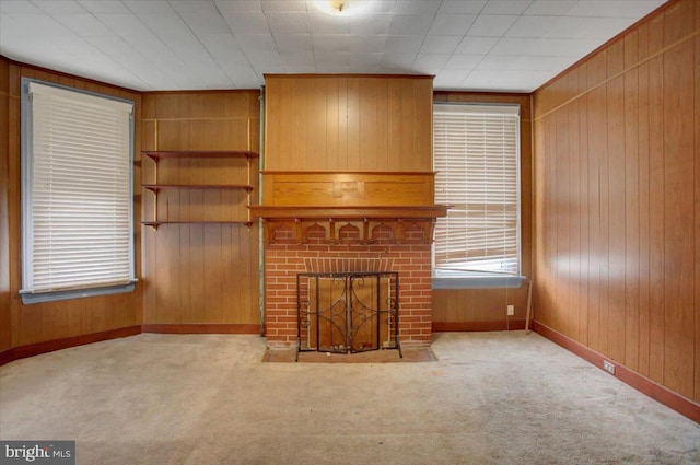 unfurnished living room with wooden walls, light carpet, and a fireplace