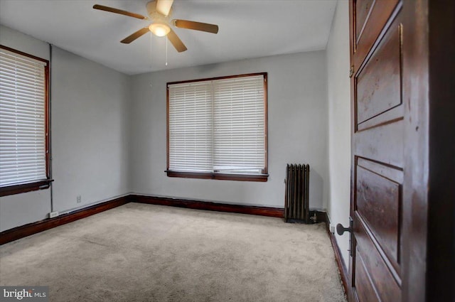 carpeted spare room with radiator and ceiling fan