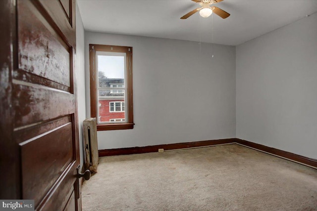 carpeted empty room featuring radiator heating unit and ceiling fan