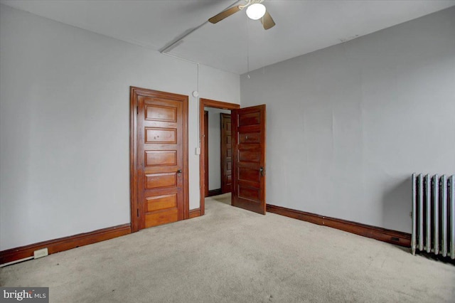 unfurnished bedroom with radiator heating unit, ceiling fan, and carpet