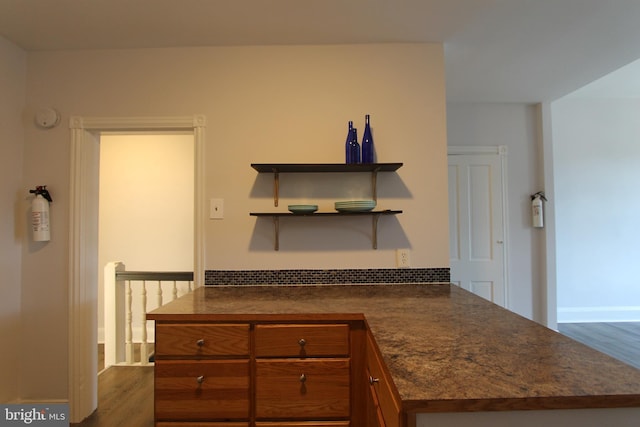 kitchen with dark countertops, dark wood-style flooring, brown cabinetry, and open shelves