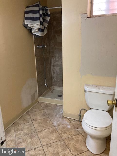 bathroom featuring baseboards, toilet, a stall shower, and tile patterned flooring