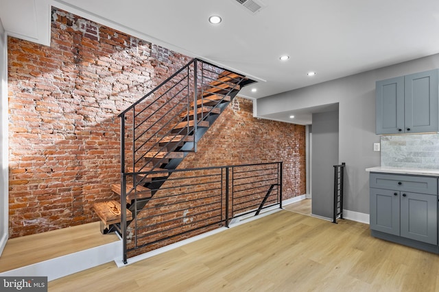 stairway featuring brick wall and wood-type flooring